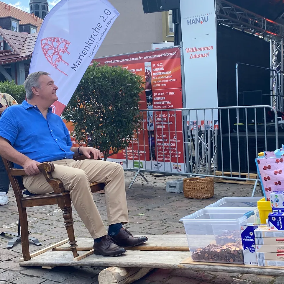 Der Oberbürgermeister sitzt auf einer eigens angefertigten Wippe, auf der linken Seite sind Spenden abgelegt.
