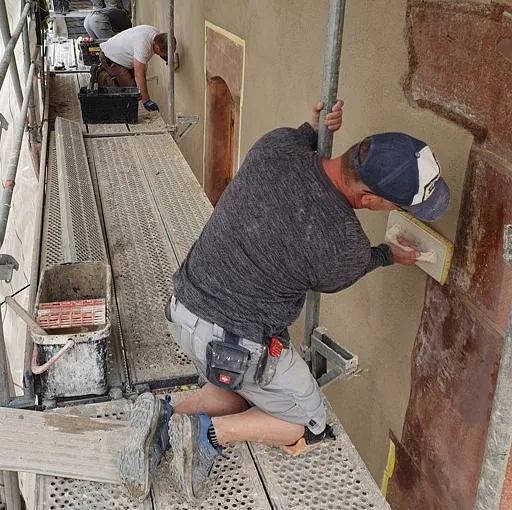 Bauarbeiter verputzen die Außenfassade neu
