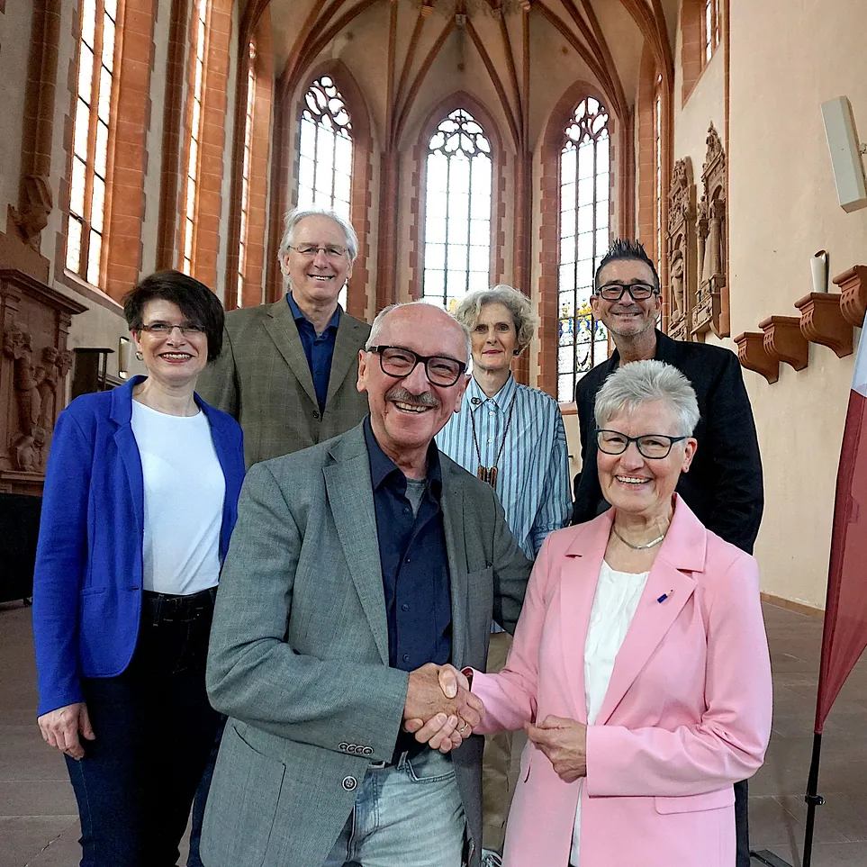 Gruppenbild Förderkreis, der scheidende Vorsitzende Horst Rühl reicht seiner Nachfolgerin Christel Sippel die Hand.